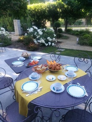 Un área de comedor al aire libre con mesas redondas, manteles amarillos y platos azules y blancos.