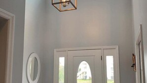 A hallway with a wooden bench, a white door with an oval window, and a hanging light fixture. - Tortuga: Spacious 5-bedroom home in Holden Beach, perfect for family fun! (Holden Beach)