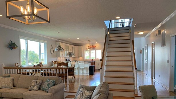 A spacious living area with a staircase leading to an upper floor, a dining area, and a kitchen. - Tortuga: Spacious 5-bedroom home in Holden Beach, perfect for family fun! (Holden Beach)