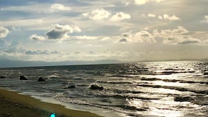 Ein Strand mit Wellen, einem klaren Himmel und fernen Bergen.