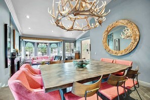 A dining area with a wooden table, red upholstered chairs, and a large chandelier.