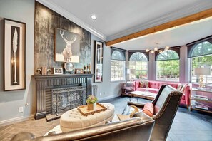 A spacious living room with a fireplace, a large window, and a cozy seating area.