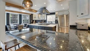 A modern kitchen with a large island, stainless steel appliances, and pendant lighting.