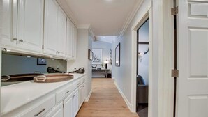 A narrow hallway with white cabinetry, a wooden countertop, and a light-colored floor.