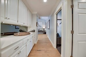A narrow hallway with white cabinetry, a wooden countertop, and a light-colored floor.