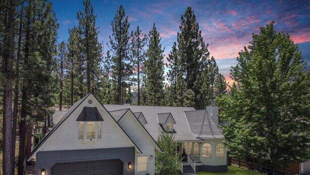 A two-story house with a garage, surrounded by a well-maintained lawn and tall trees.