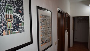 A hallway with framed artwork on the walls and doors leading to other rooms.