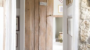 A hallway with a rustic wooden door, stone wall, and framed pictures on the wall. - Forthay Bed and Breakfast (Dursley)