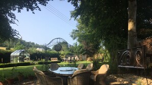A garden with a glass greenhouse, wicker furniture, and a metal sculpture. - Forthay Bed and Breakfast (Dursley)