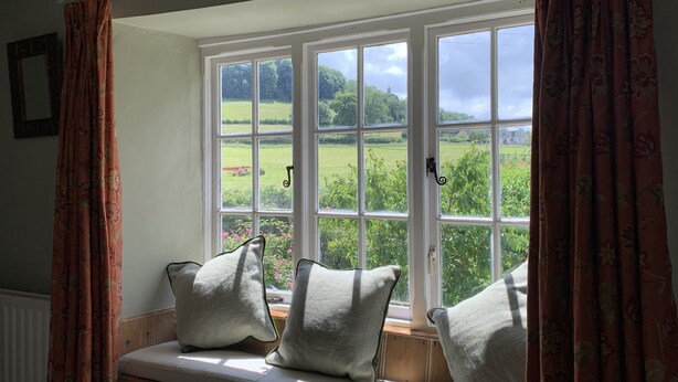 A room with a large window, a bench with cushions, and curtains. - Forthay Bed and Breakfast (Dursley)