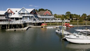 A waterfront property with a dock, a boat, and a building with multiple decks. - SeaPines, Lovely Updates,  On site pool, Free Tennis and Fitness Center, Pets OK (Hilton Head Island)