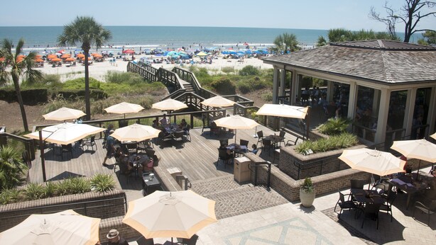 A beachside patio with outdoor seating and umbrellas, overlooking the beach and ocean. - SeaPines, Lovely Updates,  On site pool, Free Tennis and Fitness Center, Pets OK (Hilton Head Island)
