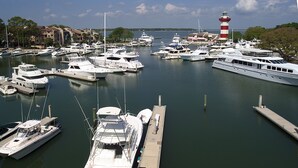 A marina with multiple boats docked at piers, a lighthouse in the background, and buildings along the waterfront. - SeaPines, Lovely Updates,  On site pool, Free Tennis and Fitness Center, Pets OK (Hilton Head Island)