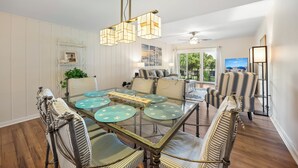 A dining area with a glass table, striped chairs, and a ceiling fan. - SeaPines, Lovely Updates,  On site pool, Free Tennis and Fitness Center, Pets OK (Hilton Head Island)