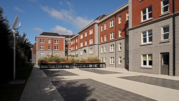A modern building with multiple floors, large windows, and a paved courtyard with benches and planters. - Griffith Rooms (Dublin)