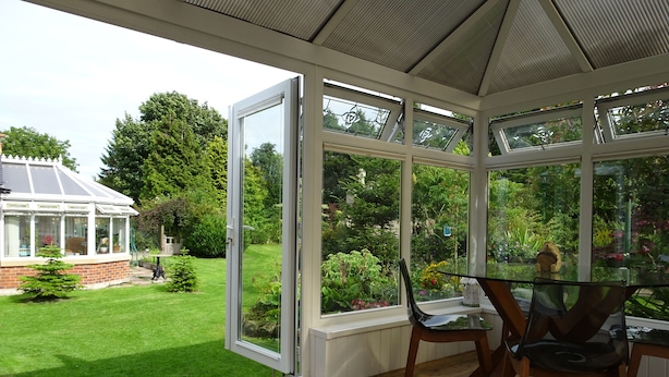 A conservatory with a glass table and chairs, a view of a garden, and a conservatory building in the background. - Gardenside Lodge self - catering dog friendly holiday home in County Durham (County Durham)