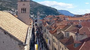 Una torre histórica con cúpula y campana, rodeada de edificios tradicionales con tejados de tejas rojas.