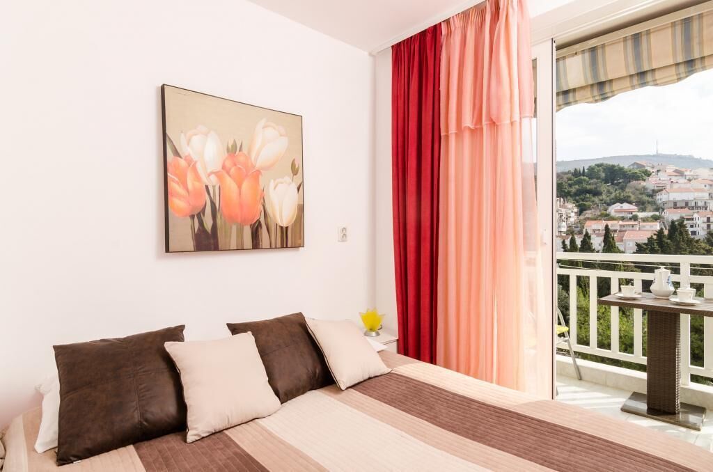 Een slaapkamer met een groot bed, uitzicht op een balkon en een schilderij aan de muur.
