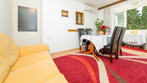 Un comedor con una mesa dispuesta para dos personas, un sofá amarillo y una alfombra roja.