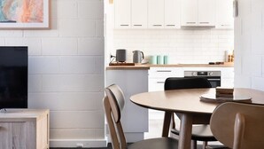 A modern kitchen with white cabinets, a wooden countertop, and a dining area with a round table and chairs.