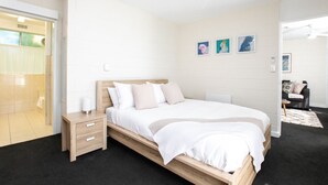 A modern bedroom with a wooden bed, a bedside table, and a nightstand. There are three framed pictures on the wall.