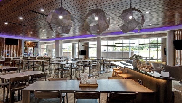 A spacious dining area with multiple tables and chairs, a reception desk, and large windows providing natural light. - SpringHill Suites by Marriott Orangeburg (Orangeburg)