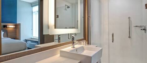 Un baño moderno con un espejo grande, dos lavamanos y una ducha con mampara de vidrio.