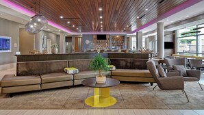 A modern lobby with a wooden ceiling, a central seating area with a round table, and a bar with a variety of bottles. - SpringHill Suites by Marriott Orangeburg (Orangeburg)