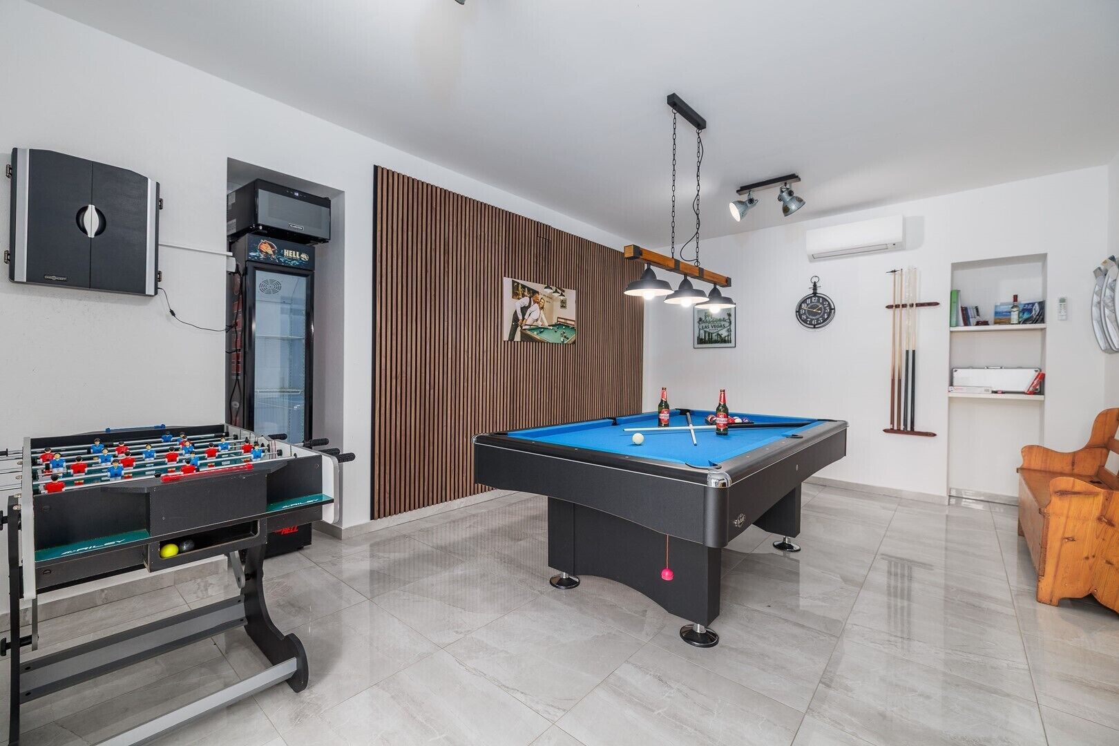 Una habitación con mesa de fútbol, mesa de billar y un porta-bolas de billar.