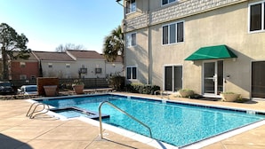 A swimming pool with a metal ladder, surrounded by a tiled deck.