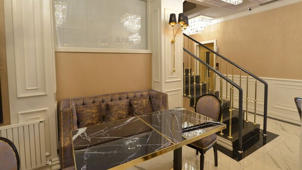 Ein Zimmer mit einem Marmortisch, einer Couch, einer Treppe und einem Chandelier.