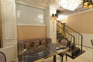 A room with a marble table, a sofa, a staircase, and a chandelier. - Santra Hotel (Istanbul)