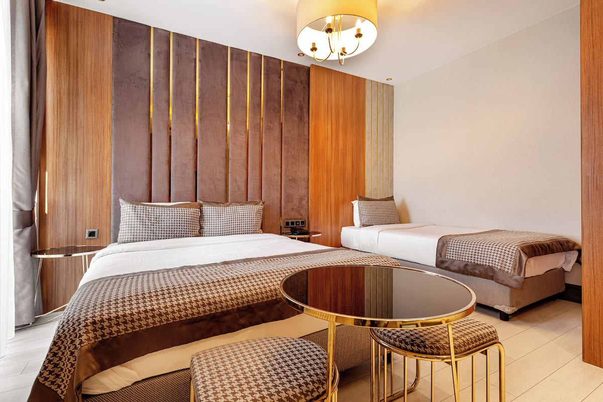 Una habitación de hotel moderna con una cama grande, un sofá cama, una mesa redonda y un televisor instalado en la pared.