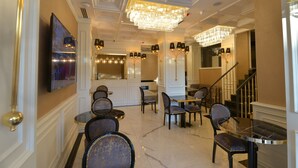 Eine geräumige Lobby mit einer Chandelüster, verschiedenen Sitzbereichen und einer Treppe.