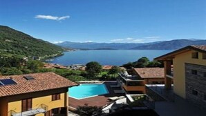 Una villa costera con piscina, casas escalonadas y vistas al mar y a las montañas.