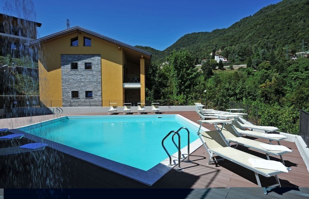 A swimming pool with lounge chairs and a building with a stone facade.