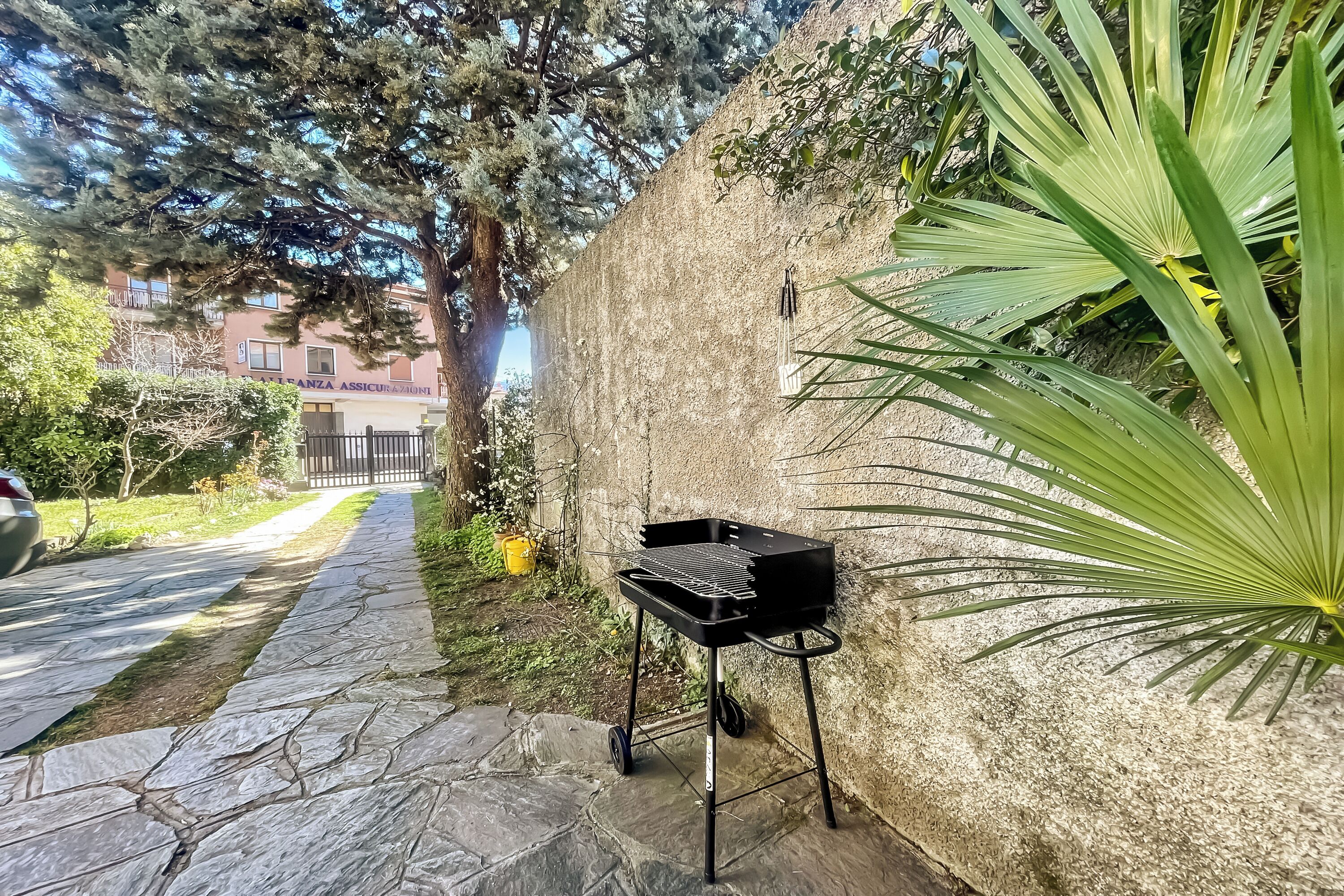 A patio area with a grill, stone pathway, and a wall with a flag.