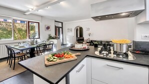 A modern kitchen with a dining area, stainless steel appliances, and a view of the outdoors. - Menaggio 57 (Menaggio)