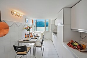 Een moderne keuken met een eethoek en uitzicht op een meer, met een gedekte tafel met borden en flessen.
