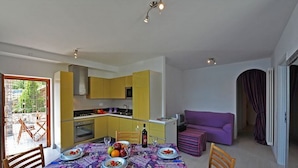 A compact living space with a dining area, kitchen, and a purple sofa. - Gera Panoramica (Gera Lario)