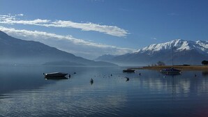 A calm lake with boats and a mountain in the background. - Gera Panoramica (Gera Lario)