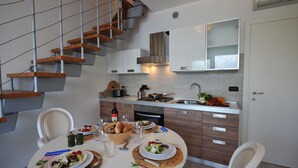 A modern kitchen with a built-in stove, white cabinets, and a wooden staircase. - Bellano Perla Apt. 8 (Bellano)