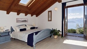 A bedroom with a bed, bedside table, lamp, and a view of the sea through a large window. - Sogni Di Bellagio ICI (Bellagio)
