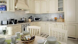 A kitchen with white cabinets, a microwave, a stove, and a dining table with chairs. - Sogni Di Bellagio ICI (Bellagio)
