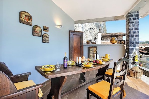 A dining area with a wooden table set for four, surrounded by chairs with yellow cushions. - La Torre Di Porlezza (Porlezza)