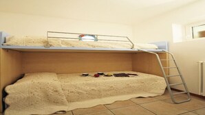 A bunk bed with a ladder, a quilted bedspread, and a small table with books and a bowl. - Residenza Vercana Giardino (Vercana)