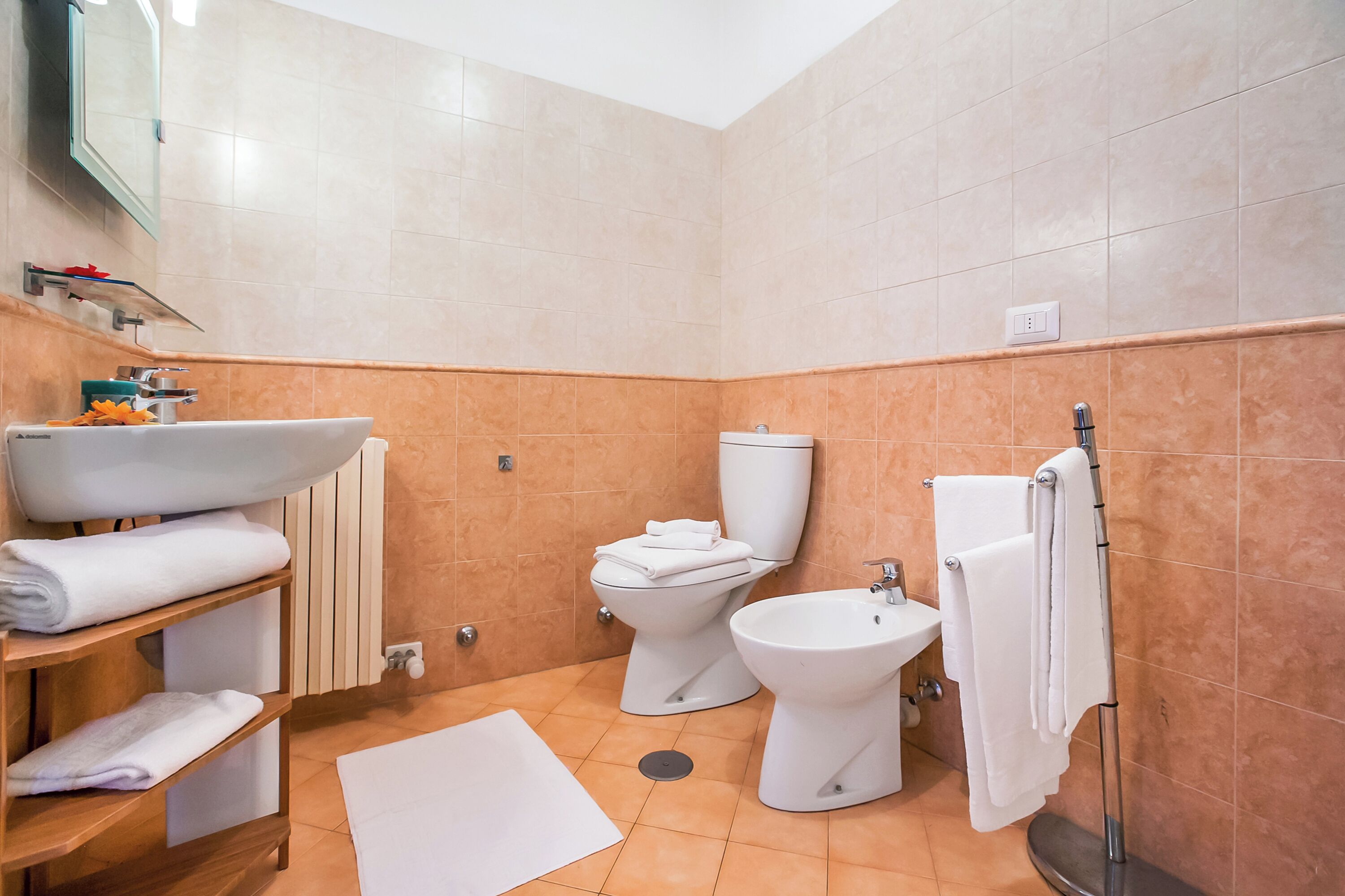 A modern bathroom with a sink, toilet, bidet, and towel rack.