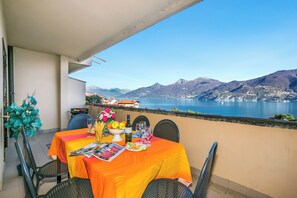 A balcony with a table set for two, overlooking a lake and mountains. - Bellavista Grande (Menaggio)