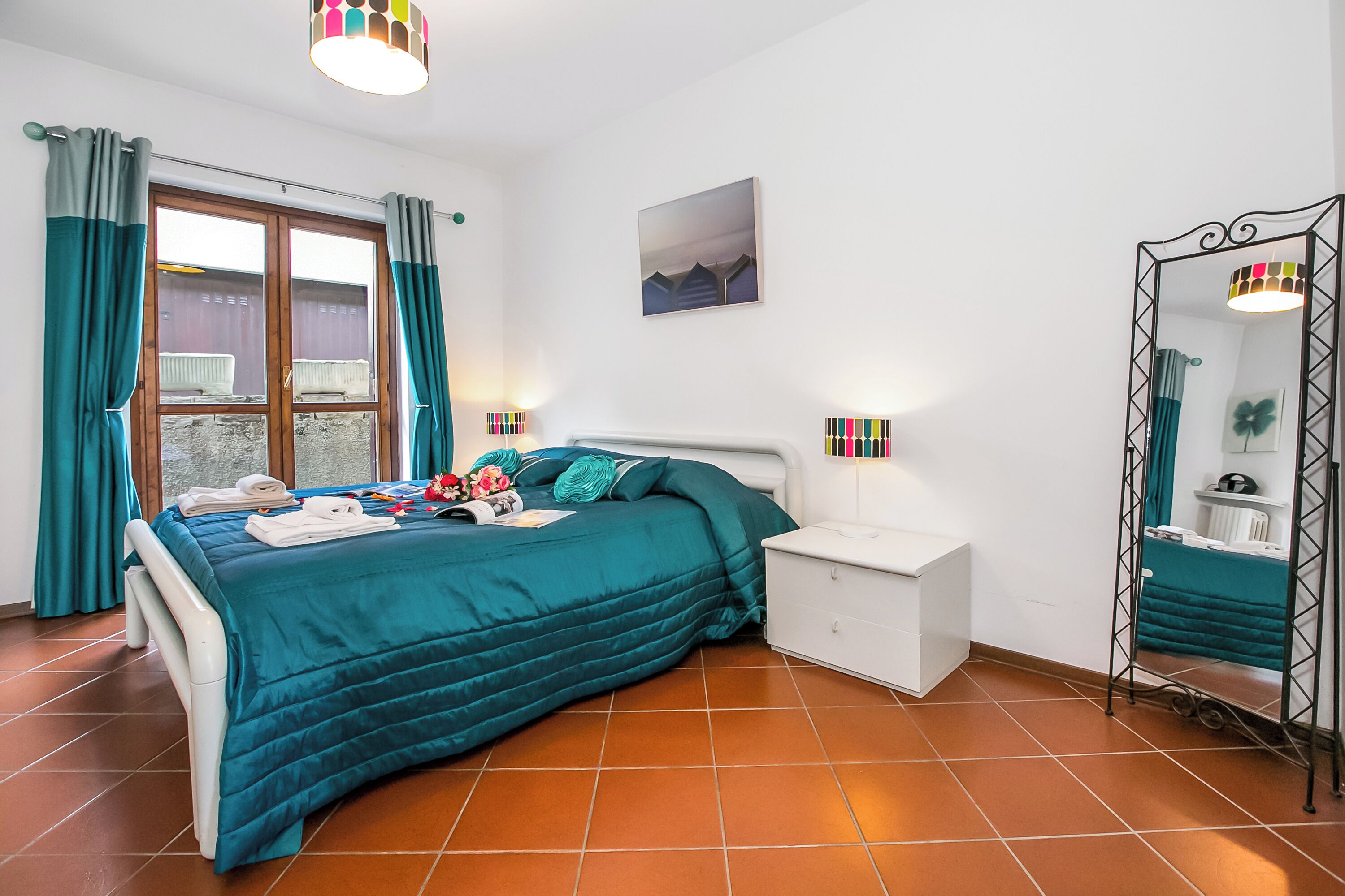 A bedroom with a bed, bedside table, and a mirror.