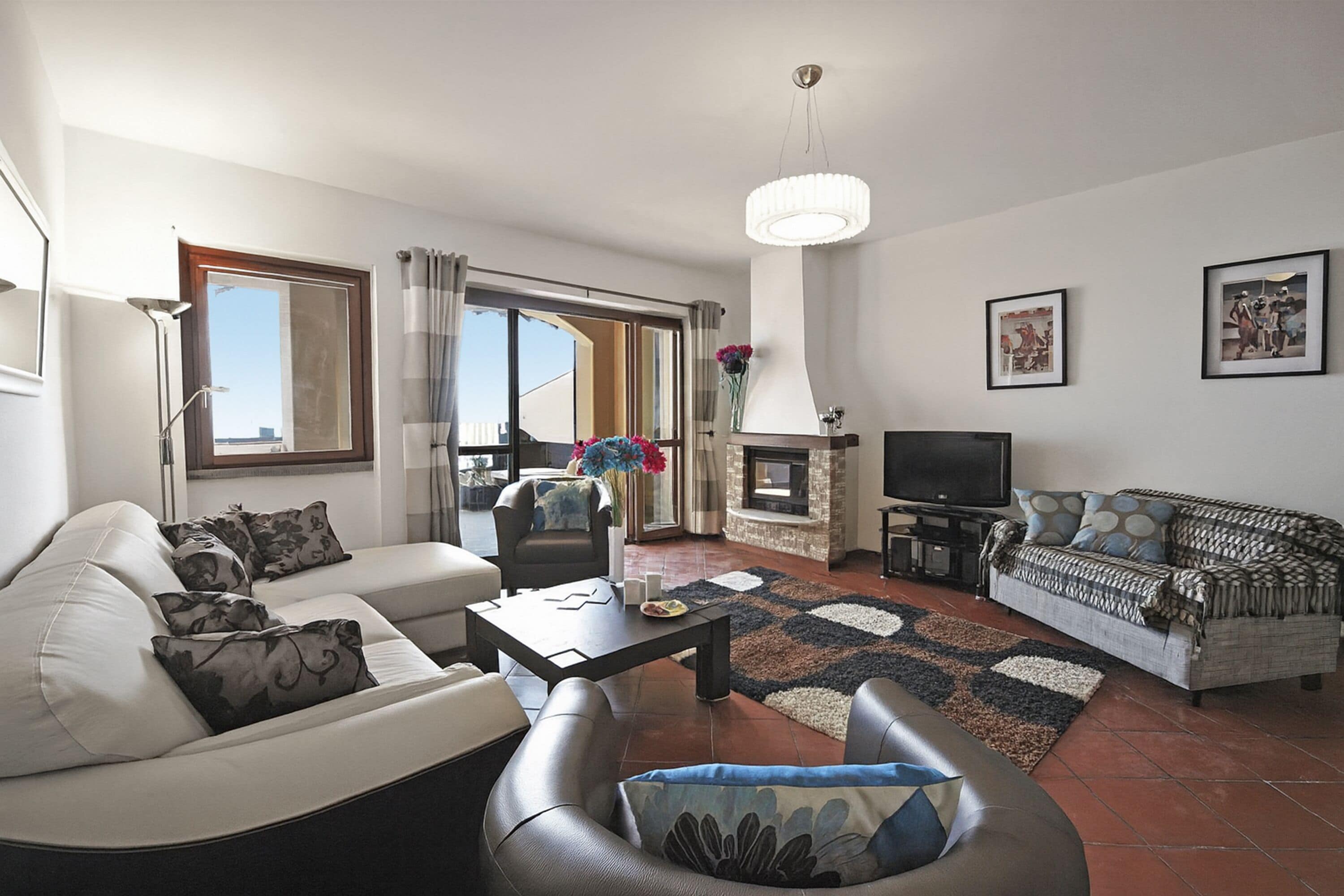 A living room with a sofa, armchairs, a coffee table, a fireplace, and a television.